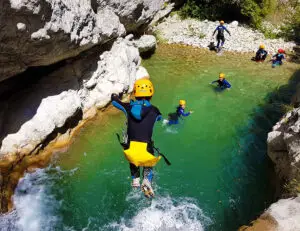 Groupe d'enfants qui sautent dans l'eau lors d'une descente de rivière en canyoning près du village de Gréolières - Les Geckos